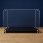 Image of the custom sized acrylic display case with a modern base, shown empty, on a wooden table with a dark blue background