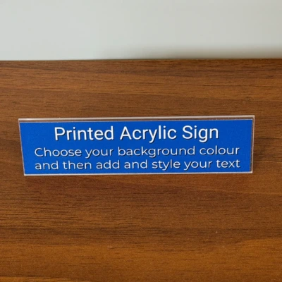 Front view of the Printed Acrylic Sign, shown on a wooden table with a grey backdrop