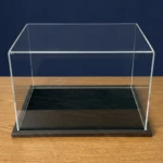 Image of an acrylic display case with a black wooden base and a black centra display area, shown empty.