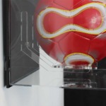 Close-up sideview image for the Acrylic Wall Display Case for a Signed football, shown with a black back, and containing a red football